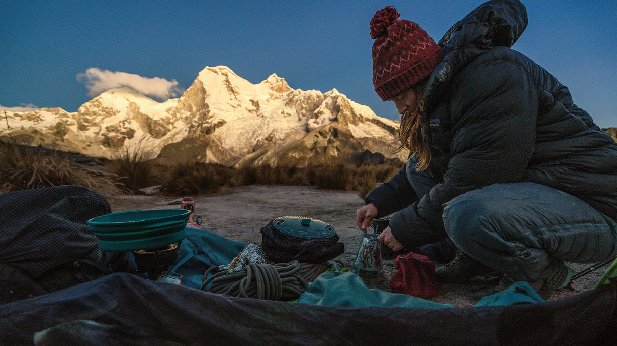 Before attempting La Esfinge, Rhiannon Williams cooks a dehydrated meal as the light fades on Mount Huandoy in the distance. Peru.